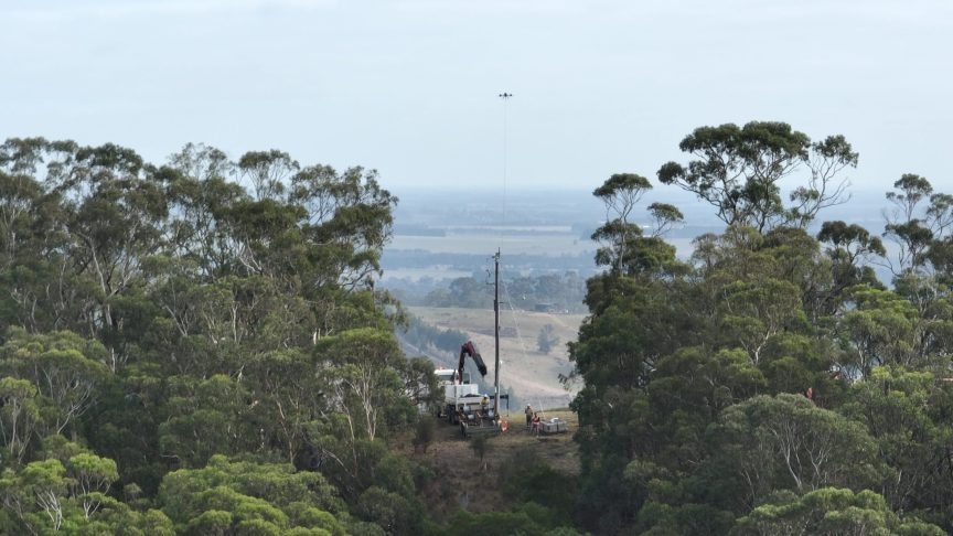 Image of a drone in the air holding a guide wire